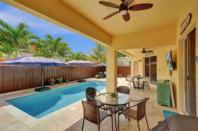 view of swimming pool featuring a fenced in pool, a fenced backyard, a ceiling fan, outdoor dining space, and a patio