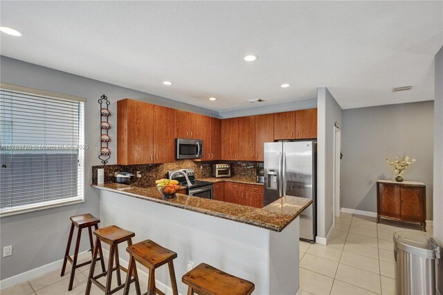 kitchen featuring a peninsula, visible vents, appliances with stainless steel finishes, brown cabinets, and light tile patterned floors