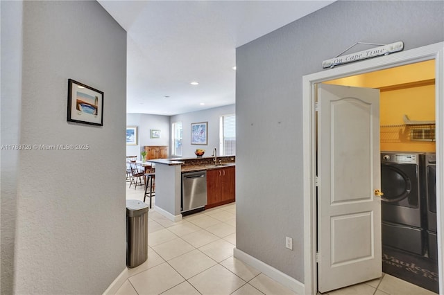 corridor featuring a sink, light tile patterned flooring, baseboards, recessed lighting, and independent washer and dryer