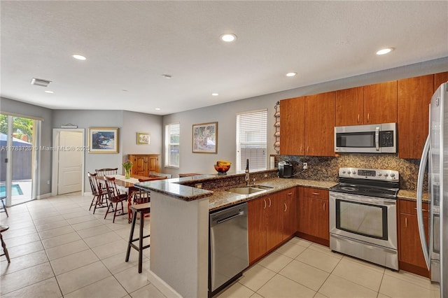 kitchen featuring stainless steel appliances, visible vents, a sink, and brown cabinets
