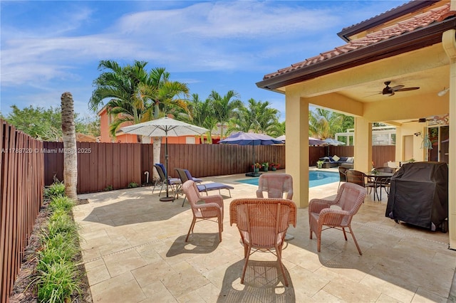 view of patio with grilling area, a fenced backyard, a fenced in pool, and a ceiling fan
