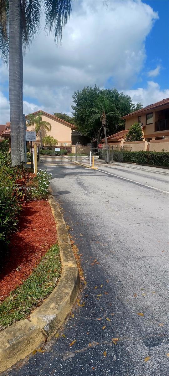 view of road with a gate, a gated entry, and curbs