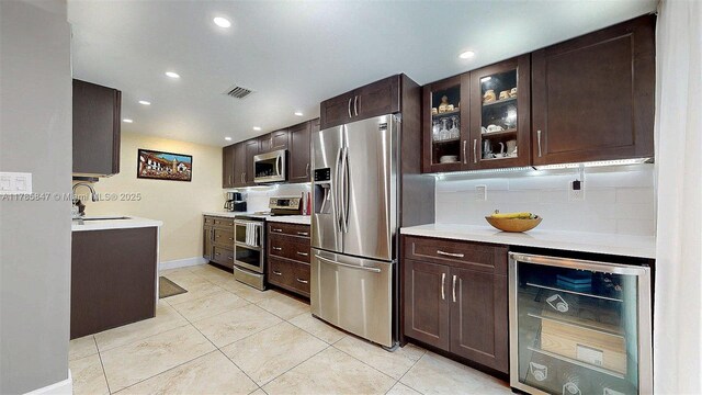 11282 SW 9th Ct, Pembroke Pines, FL 33025 - kitchen featuring appliances with stainless steel finishes, wine cooler, a sink, dark brown cabinetry, and tasteful backsplash