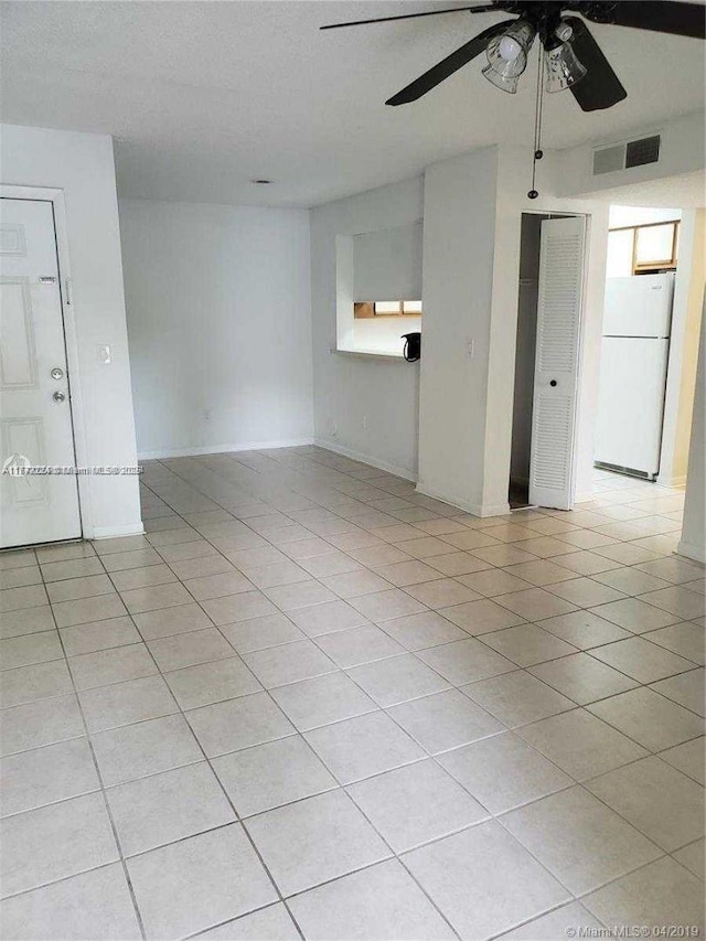 unfurnished room with visible vents, baseboards, ceiling fan, and light tile patterned floors