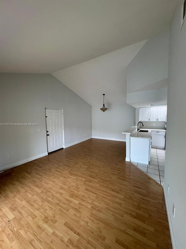 bonus room featuring high vaulted ceiling, light wood-style floors, baseboards, and a sink