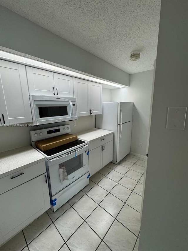 kitchen with light countertops, white appliances, white cabinetry, and light tile patterned flooring