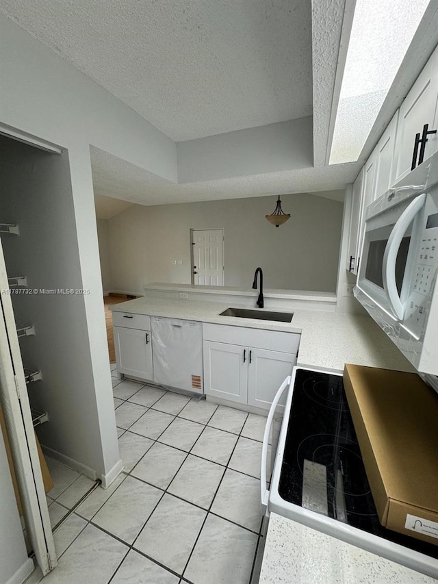 kitchen with a textured ceiling, a sink, white appliances, light countertops, and white cabinetry