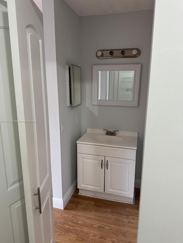 bathroom featuring baseboards, wood finished floors, and vanity