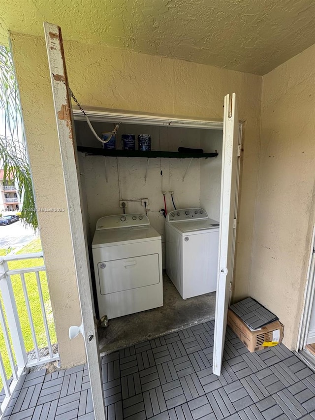 laundry area featuring a textured wall, washer and clothes dryer, and laundry area