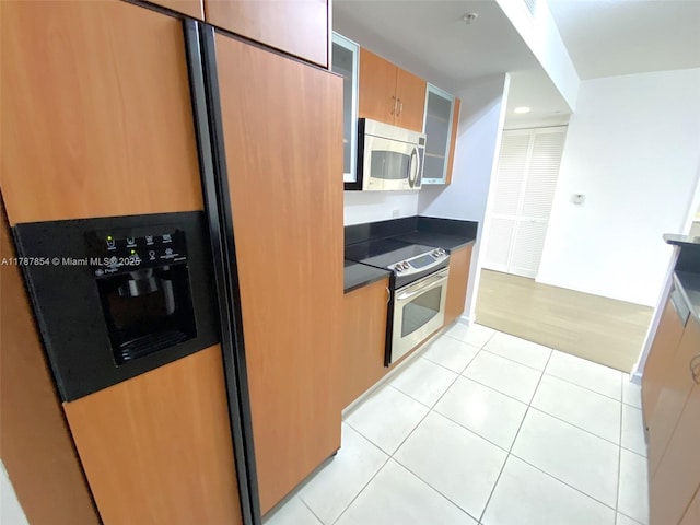 18800 NE 29th Ave Unit 1028, Aventura, FL 33180 - kitchen with dark countertops, glass insert cabinets, stainless steel appliances, and light tile patterned floors