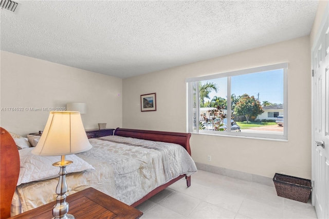 bedroom featuring baseboards, a textured ceiling, and visible vents