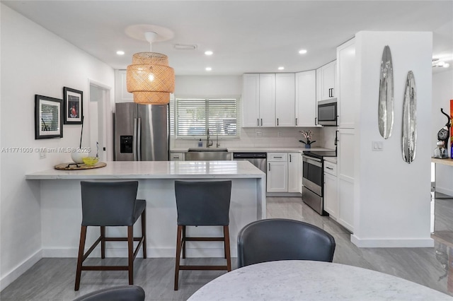 1990 NE 35th St, Lighthouse Point, FL 33064 - kitchen featuring a sink, a breakfast bar, stainless steel appliances, a peninsula, and white cabinetry