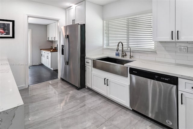 1990 NE 35th St, Lighthouse Point, FL 33064 - kitchen with white cabinets, a sink, decorative backsplash, light stone counters, and appliances with stainless steel finishes