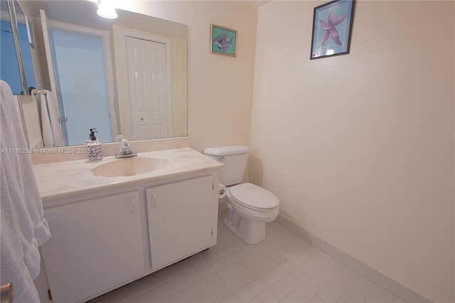 bathroom with toilet, vanity, tile patterned floors, and baseboards