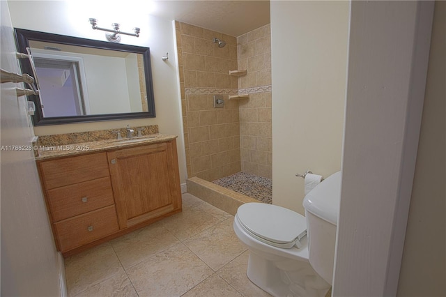 bathroom with a tile shower, tile patterned flooring, vanity, and toilet