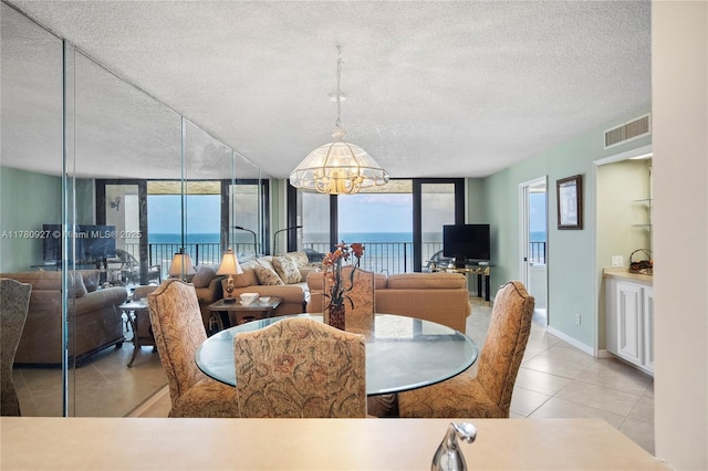 10000 S Ocean Dr Unit 703, Jensen Beach, FL 34957 - dining space featuring a textured ceiling, a chandelier, expansive windows, and tile patterned flooring
