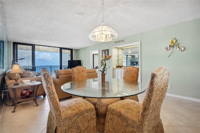 10000 S Ocean Dr Unit 703, Jensen Beach, FL 34957 - dining space with a chandelier, light tile patterned floors, a textured ceiling, and baseboards
