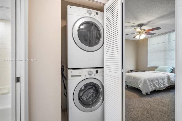 10000 S Ocean Dr Unit 703, Jensen Beach, FL 34957 - washroom featuring stacked washing machine and dryer, a ceiling fan, carpet flooring, and a textured ceiling