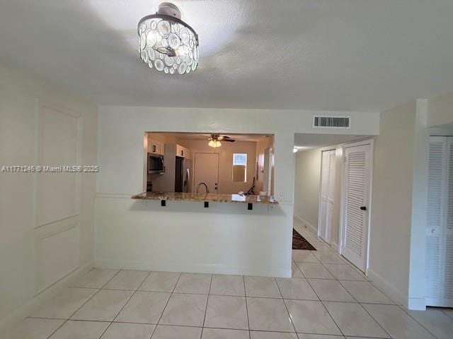 6101 N Falls Circle Dr Unit 312, Lauderhill, FL 33319 - kitchen with fridge, stainless steel microwave, light tile patterned floors, a peninsula, and a ceiling fan