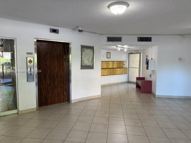 6101 N Falls Circle Dr Unit 312, Lauderhill, FL 33319 - unfurnished room with a textured ceiling, light tile patterned floors, healthy amount of natural light, and elevator