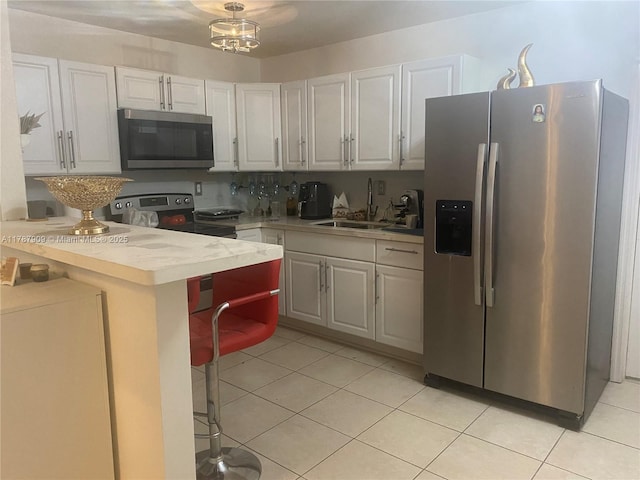 18714 SW 306th Ter, Homestead, FL 33030 - kitchen featuring appliances with stainless steel finishes, a sink, light countertops, light tile patterned flooring, and white cabinets