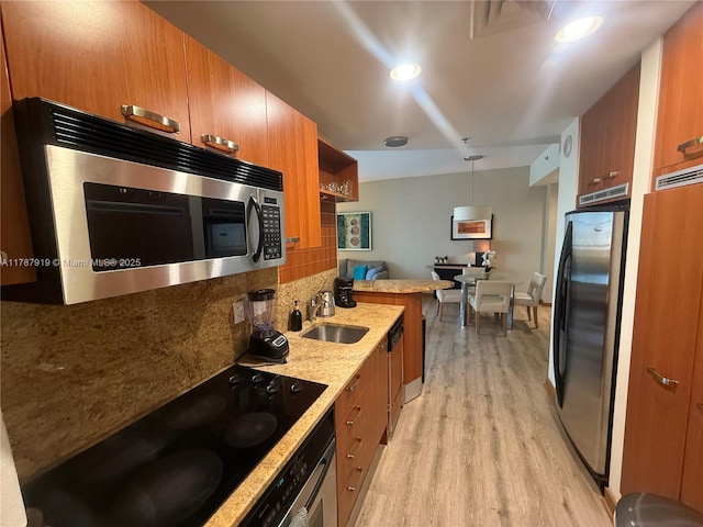 1395 Brickell Ave Unit 3211, Miami, FL 33131 - kitchen featuring appliances with stainless steel finishes, light wood-type flooring, brown cabinets, tasteful backsplash, and light stone countertops