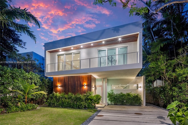 4039 Ventura Ave, Miami, FL 33133 - back of property at dusk with a lawn, a balcony, and stucco siding