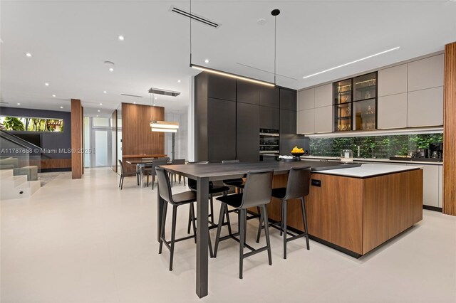 4039 Ventura Ave, Miami, FL 33133 - kitchen featuring a large island, tasteful backsplash, visible vents, modern cabinets, and glass insert cabinets