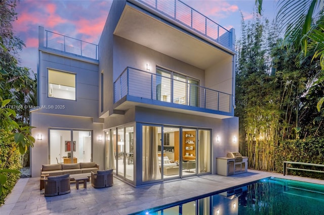 4039 Ventura Ave, Miami, FL 33133 - back of house at dusk featuring stucco siding, a patio area, and a balcony