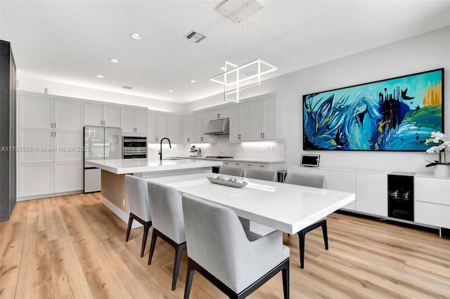 8608 Torrey Isles Ter, Boca Raton, FL 33496 - kitchen with stainless steel appliances, light wood-type flooring, light countertops, under cabinet range hood, and tasteful backsplash