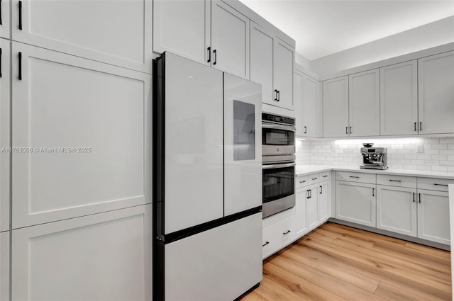 8608 Torrey Isles Ter, Boca Raton, FL 33496 - kitchen with freestanding refrigerator, light countertops, stainless steel double oven, backsplash, and light wood-style flooring