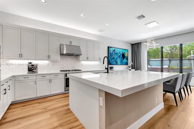 8608 Torrey Isles Ter, Boca Raton, FL 33496 - kitchen with under cabinet range hood, tasteful backsplash, light countertops, light wood-type flooring, and recessed lighting