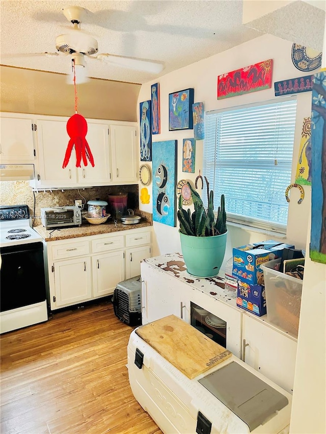 kitchen featuring light wood finished floors, a textured ceiling, tasteful backsplash, white electric range, and white cabinetry