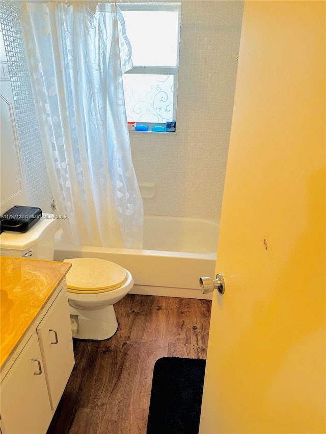 full bath featuring wood finished floors, toilet, vanity, and shower / bathtub combination with curtain