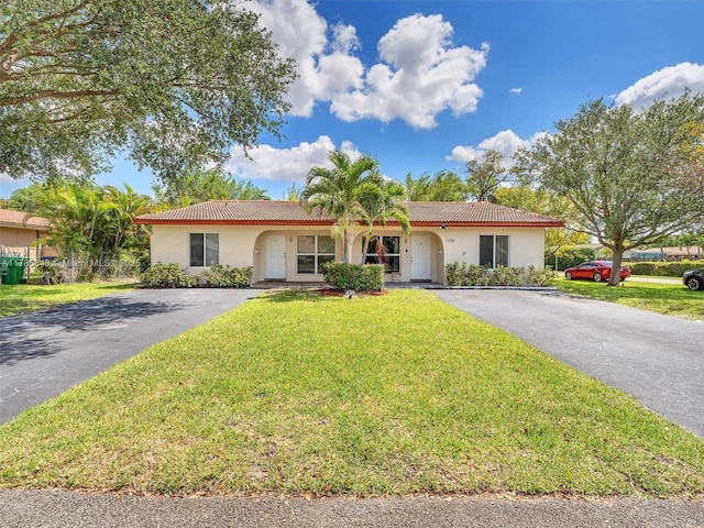 ranch-style home with a tile roof, a front lawn, aphalt driveway, and stucco siding
