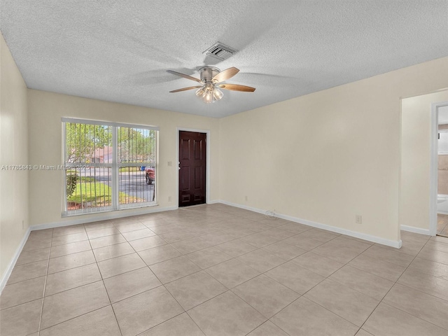 spare room with ceiling fan, a textured ceiling, visible vents, and light tile patterned floors