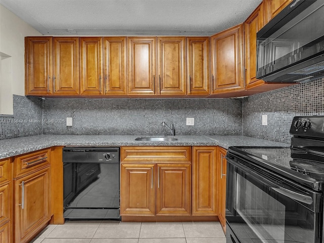 kitchen featuring brown cabinets, light tile patterned floors, a sink, and black appliances