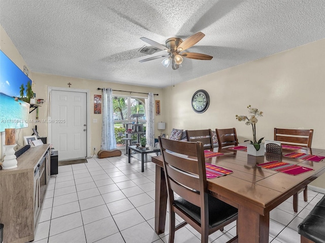 dining area with light tile patterned flooring, a textured ceiling, visible vents, and a ceiling fan