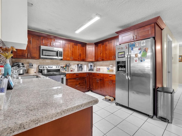 kitchen with stainless steel appliances, a textured ceiling, a sink, backsplash, and light tile patterned floors