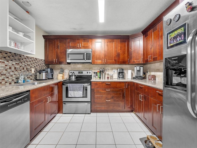 kitchen featuring a textured ceiling, a sink, decorative backsplash, light tile patterned floors, and stainless steel appliances