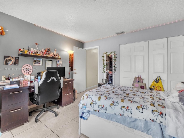 bedroom with visible vents, a textured ceiling, a closet, and light tile patterned floors