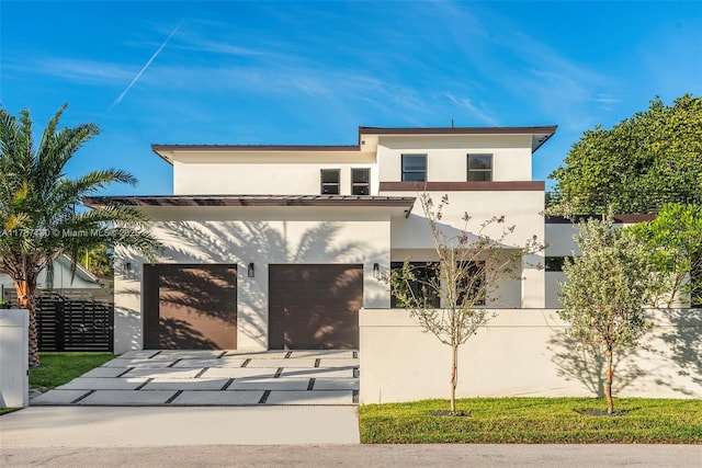 modern home featuring concrete driveway, fence, a garage, and stucco siding