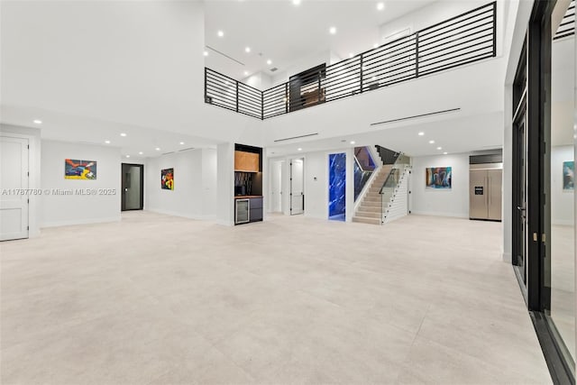 unfurnished living room featuring baseboards, a towering ceiling, stairs, and elevator
