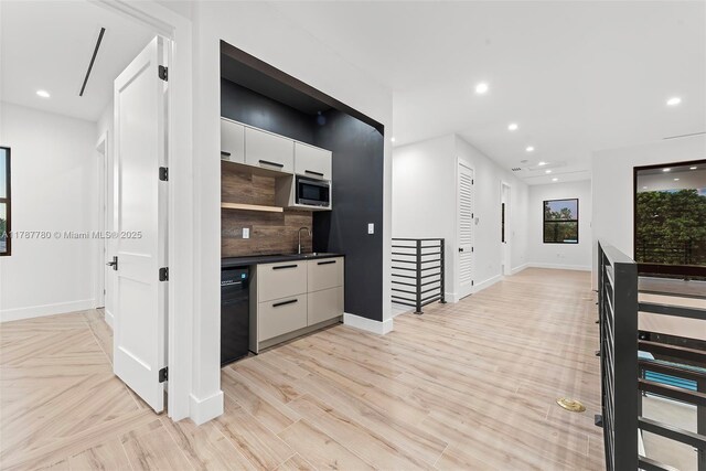 kitchen featuring modern cabinets, stainless steel microwave, black dishwasher, and a sink