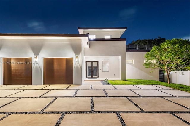 view of front of home with french doors, stucco siding, and fence