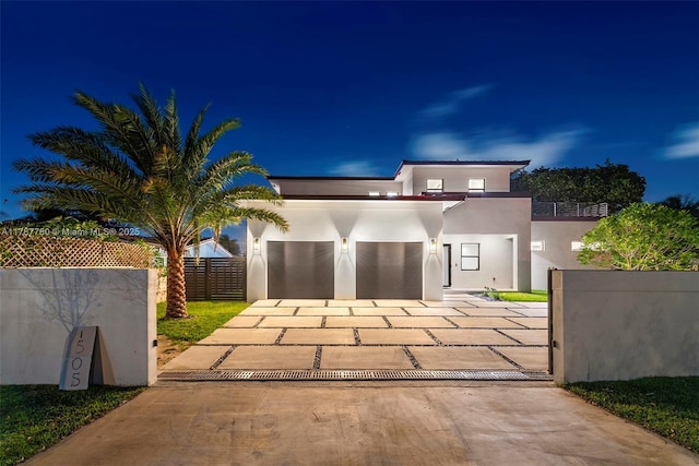 modern home featuring concrete driveway, stucco siding, and fence