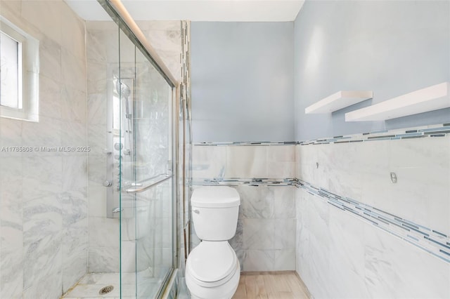 full bathroom with toilet, a stall shower, and tile walls