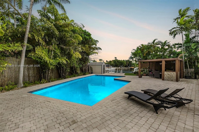 view of swimming pool with a patio area, a storage shed, a fenced backyard, an outdoor structure, and a fenced in pool