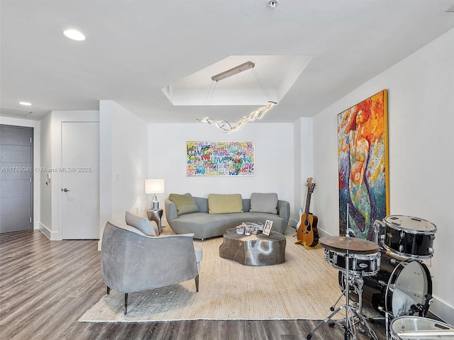 living room with wood finished floors, attic access, a tray ceiling, baseboards, and recessed lighting