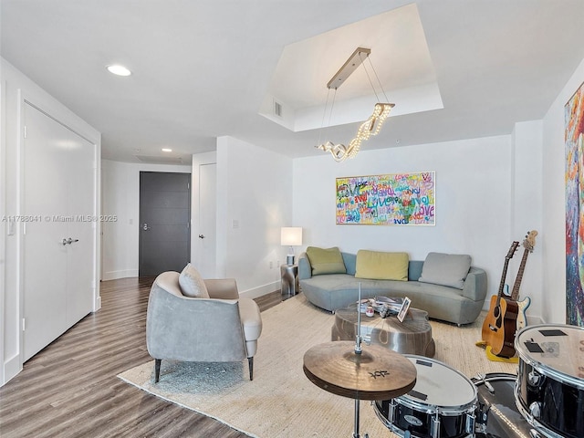 living room with recessed lighting, a raised ceiling, wood finished floors, visible vents, and baseboards